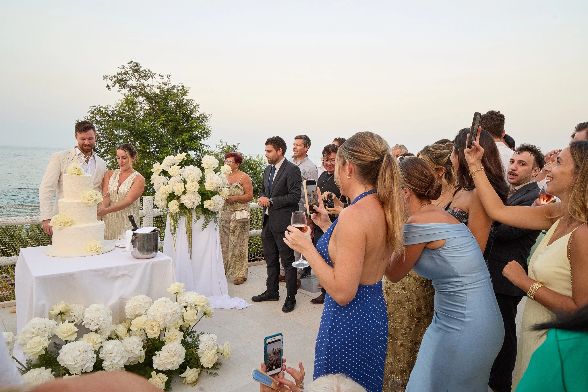 Cake cutting with guests overlooking the sea